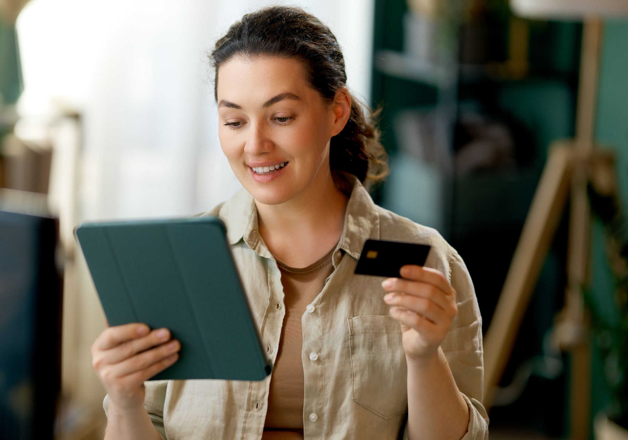 Woman shopping online on an iPad using a credit card.