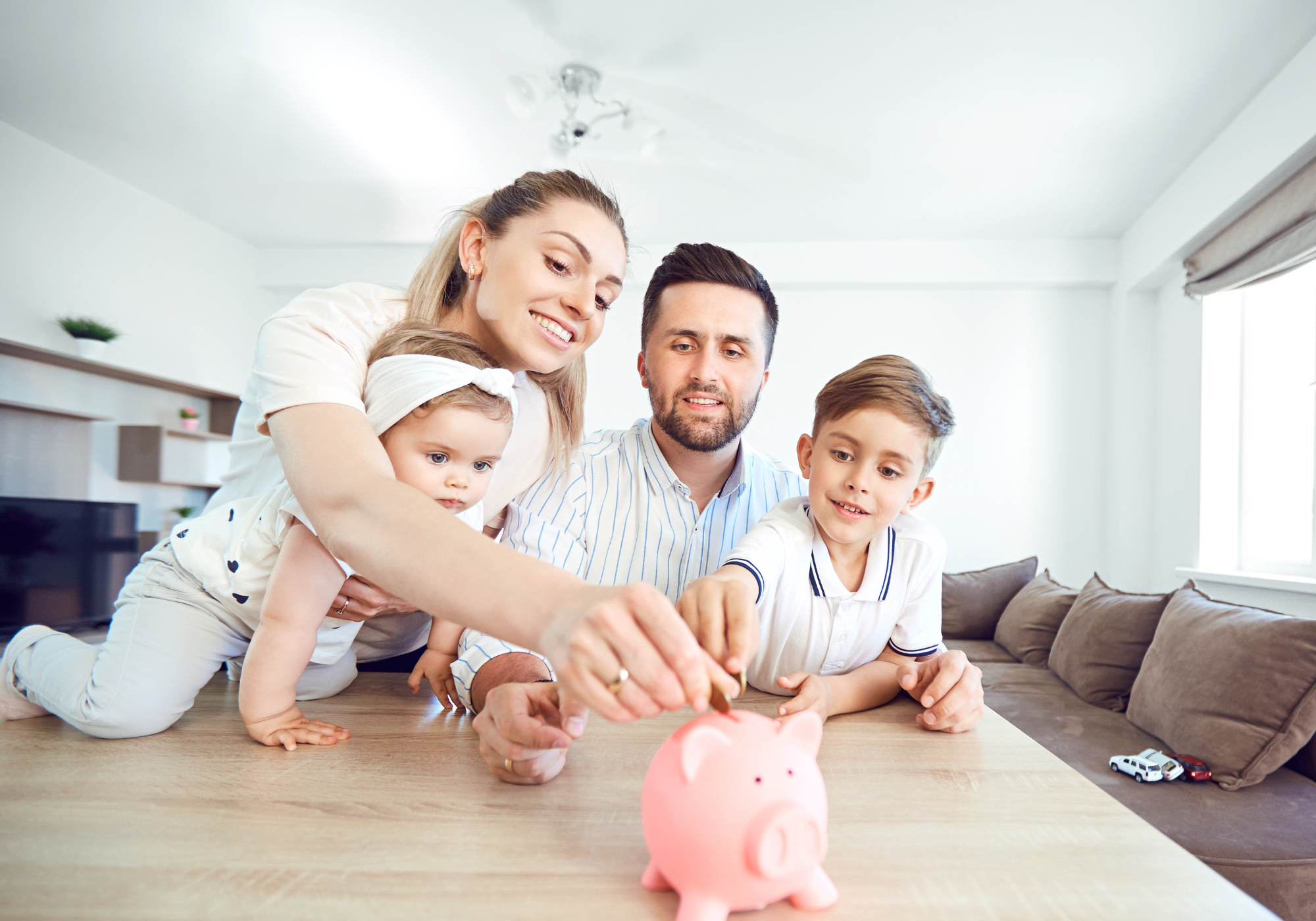 Family teaching children how to save money by putting savings in piggy bank.