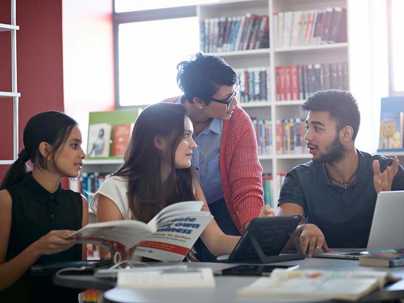Group of college students studying in library.